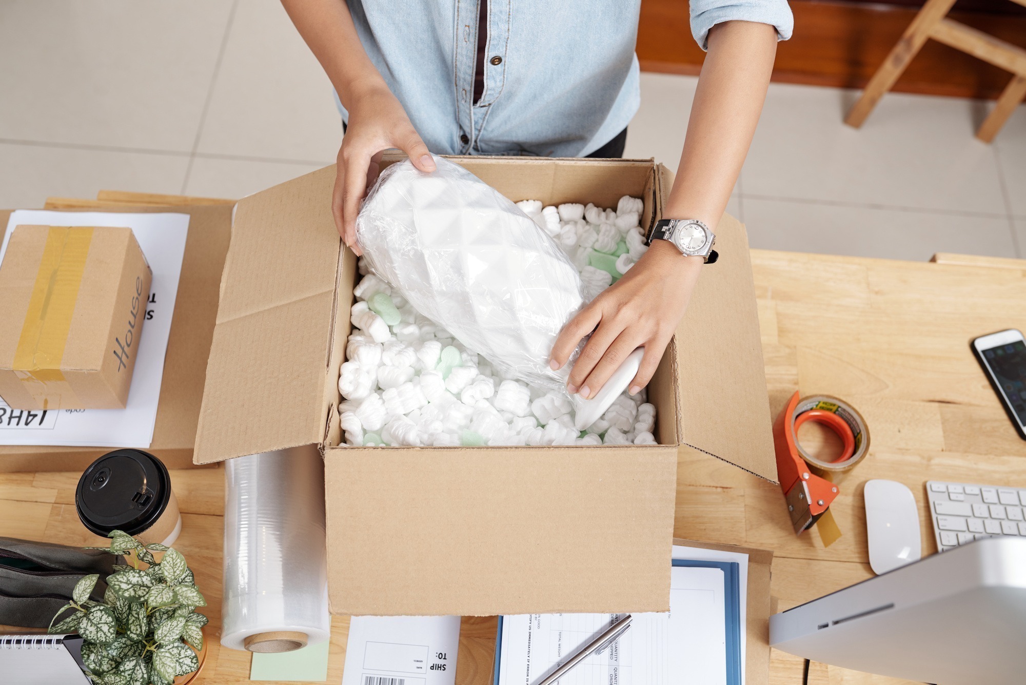 Small business owner packing vase to send it to customer, view from above