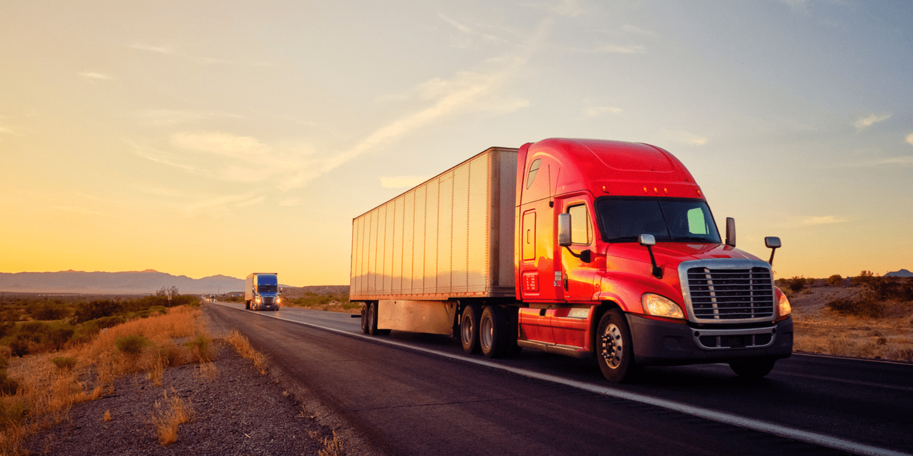 Long haul freight truck driving across the desert at sunset